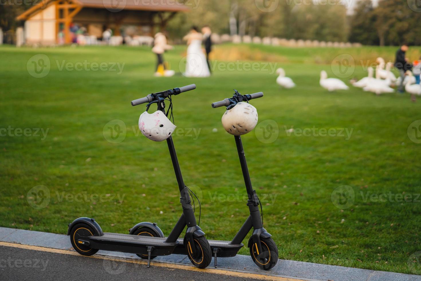 two electric kick scooters or e-scooter parked on the sidelines road photo
