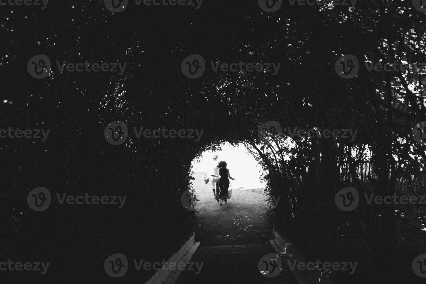 couple walking through the tunnel of trees photo