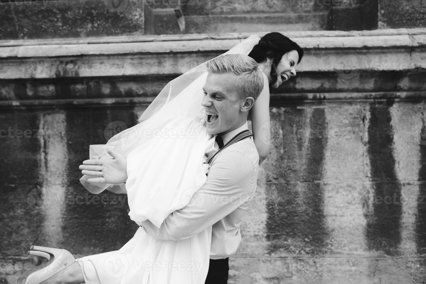 groom carries bride in his arms photo