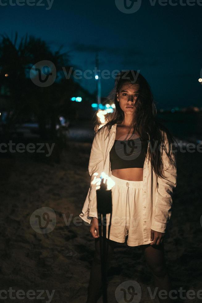 Young woman with torchlight on the beach at night photo