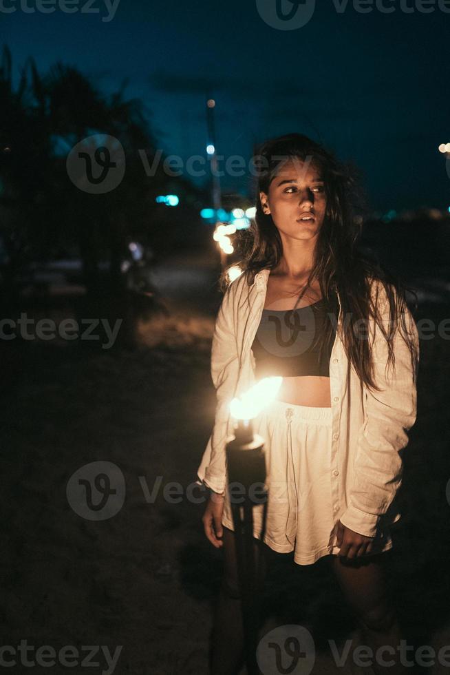 mujer joven con antorchas en la playa por la noche foto