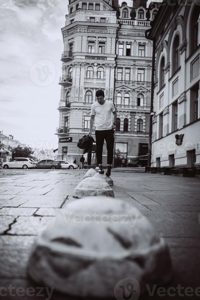 chico parado en la calle de la ciudad, mira la cámara y alrededor foto