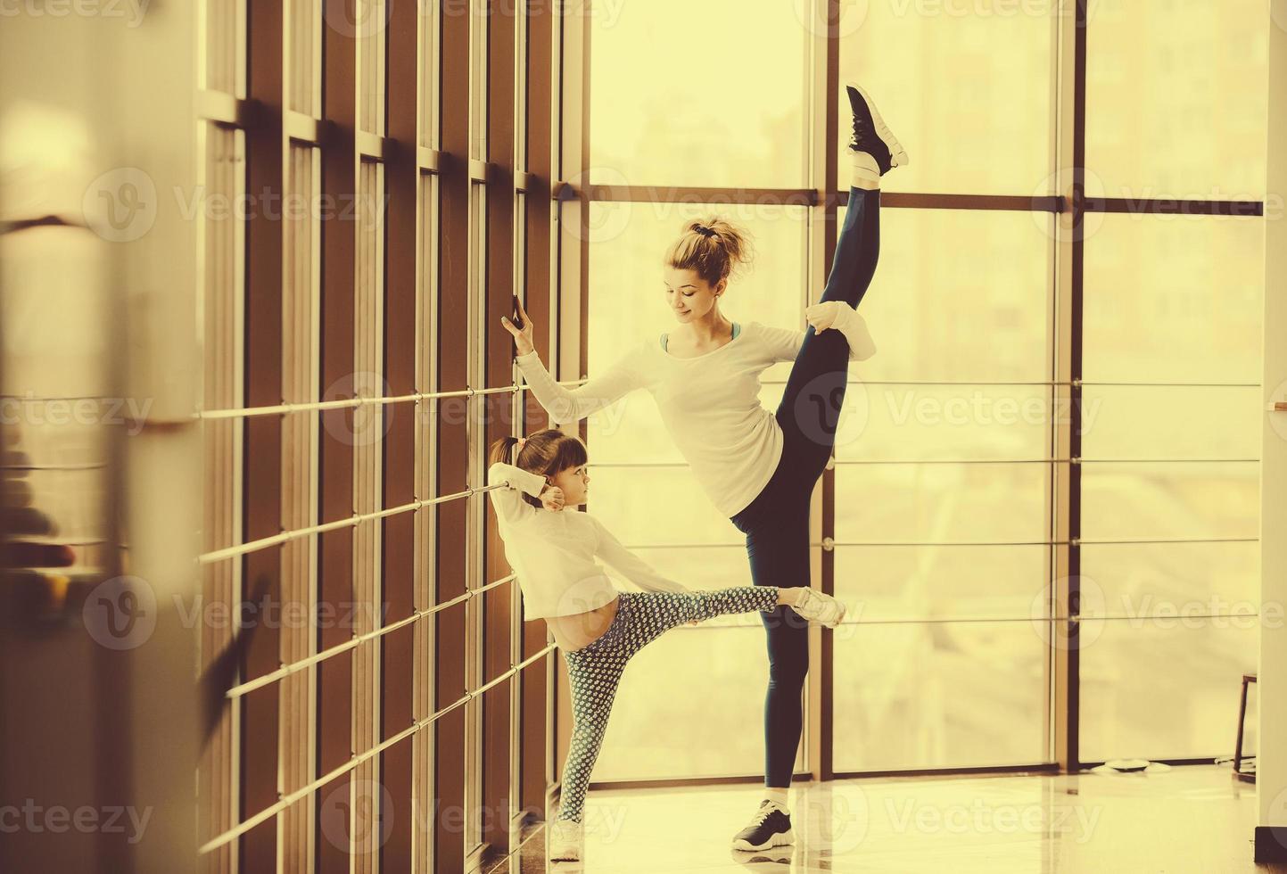 Mother learning daughter to make a high leg strech photo