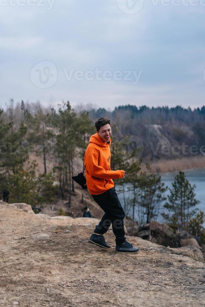 A young man standing on the edge of a cliff poses for the camera photo
