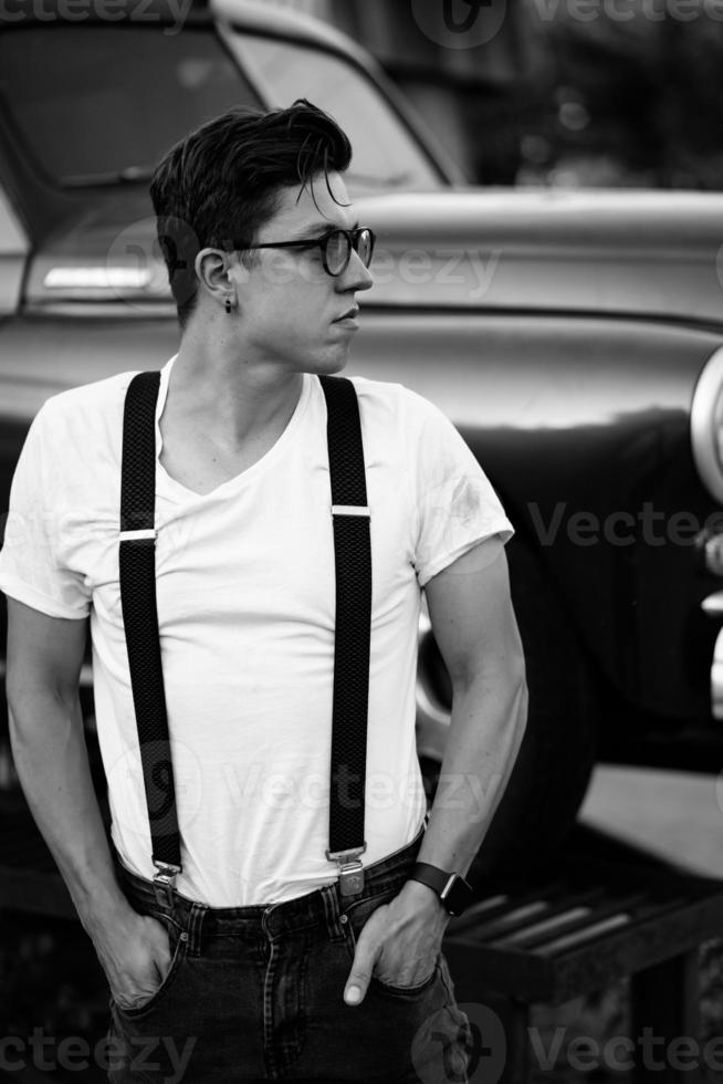 Guy in a shirt with suspenders posing at the retro car photo