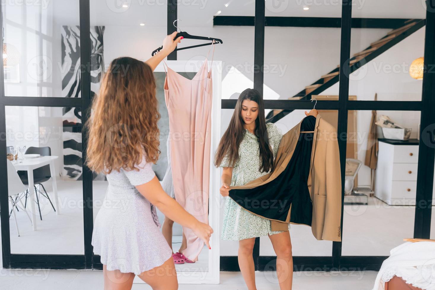 Two women choose and try on clothes at home photo