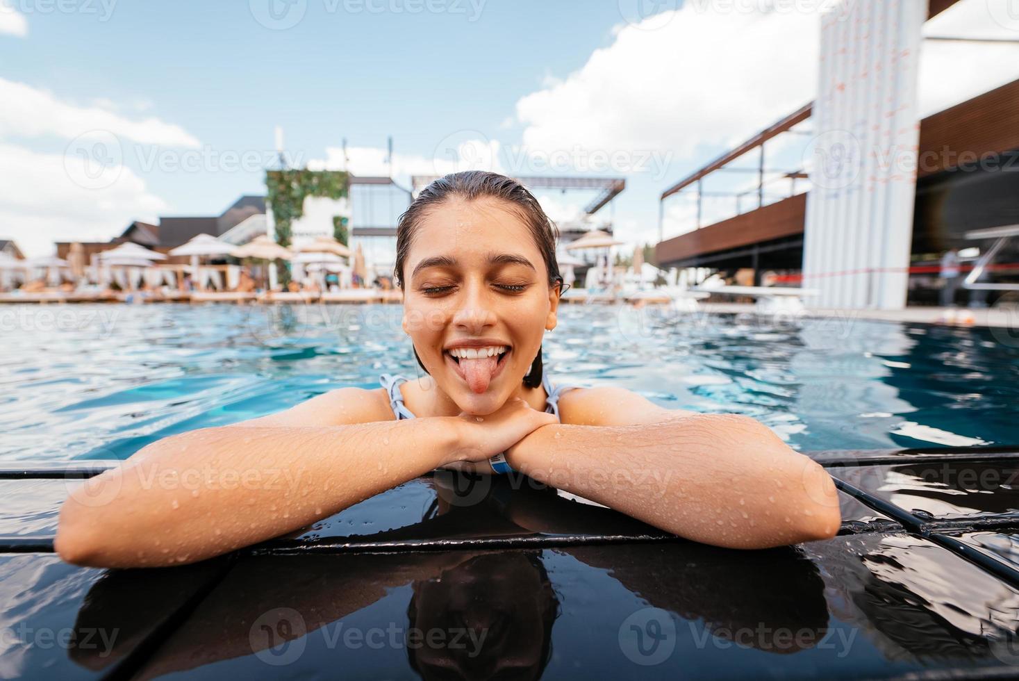 mujer joven descansando al borde de la piscina foto