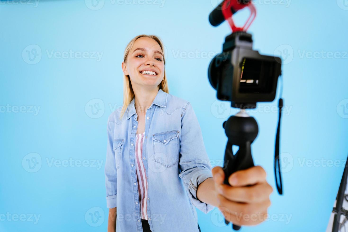 Beautiful girl blogger relieves itself at camera isolated blue background photo
