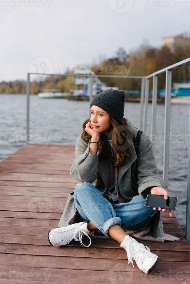 Young pretty girl on wooden bench on old pier photo