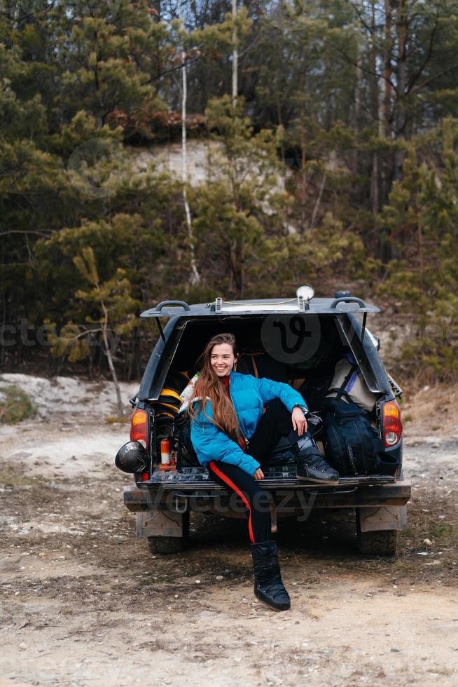 Young woman enjoying nature while sitting in the car trunk photo