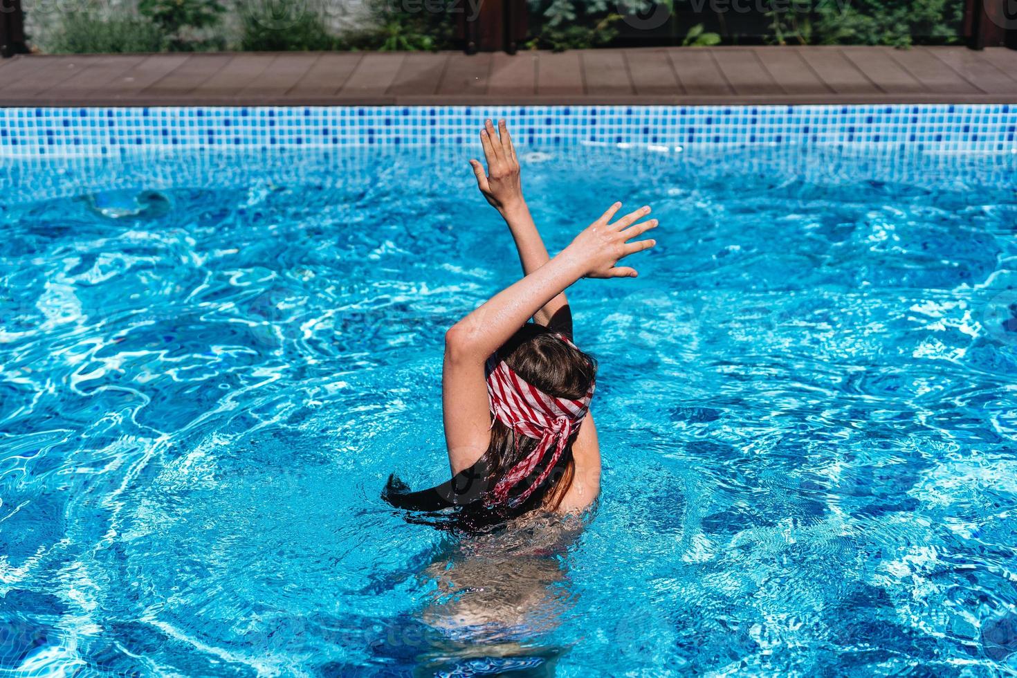 Beautiful teenage girl relaxing in pool water photo