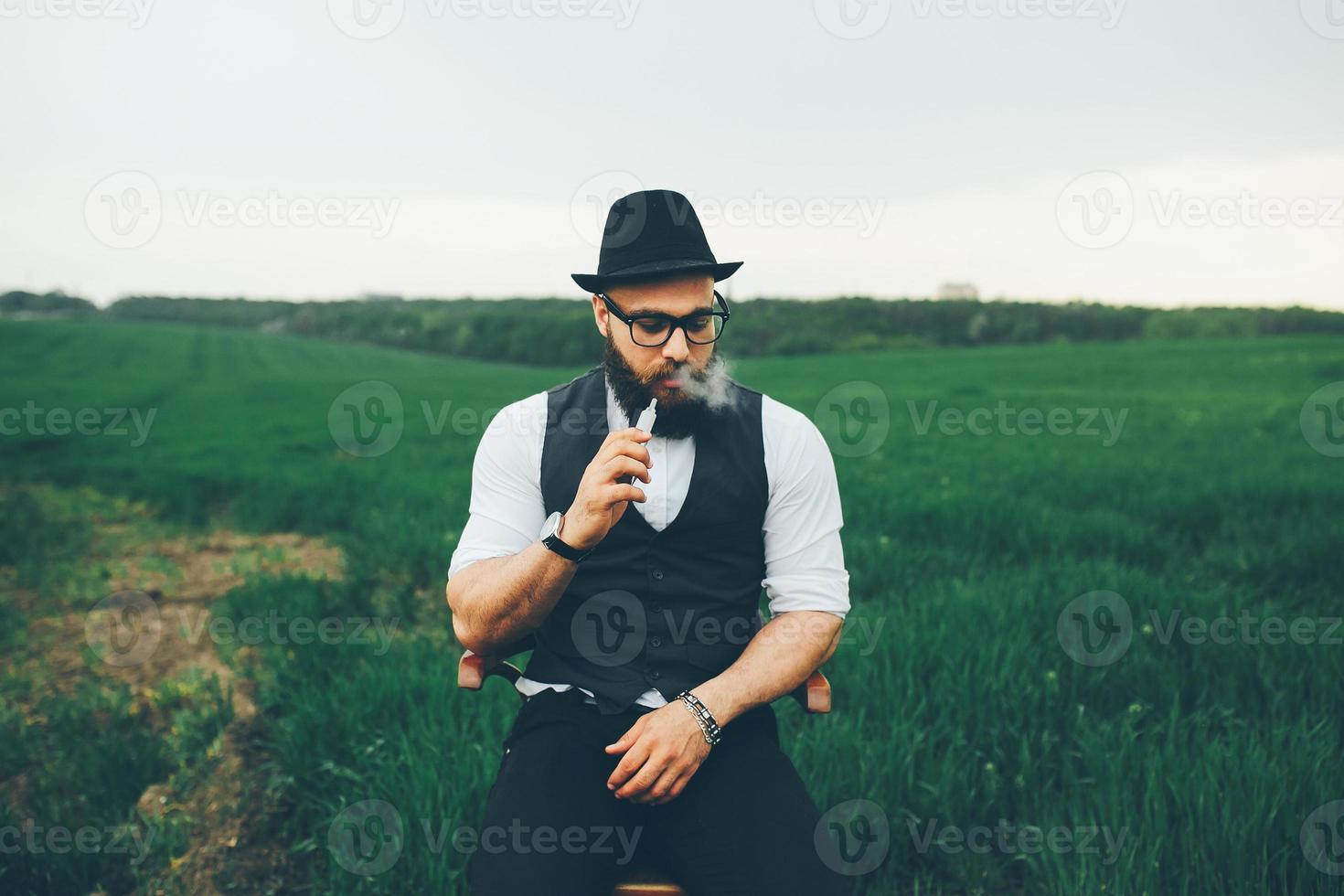 man with a beard smokes electronic cigarette photo