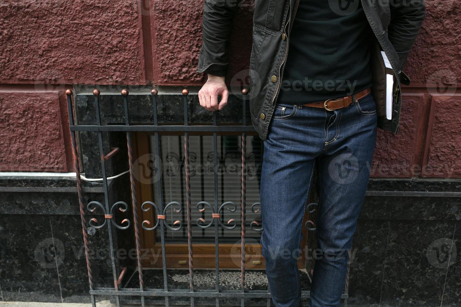 Male model in jeans on the background of a red wall photo