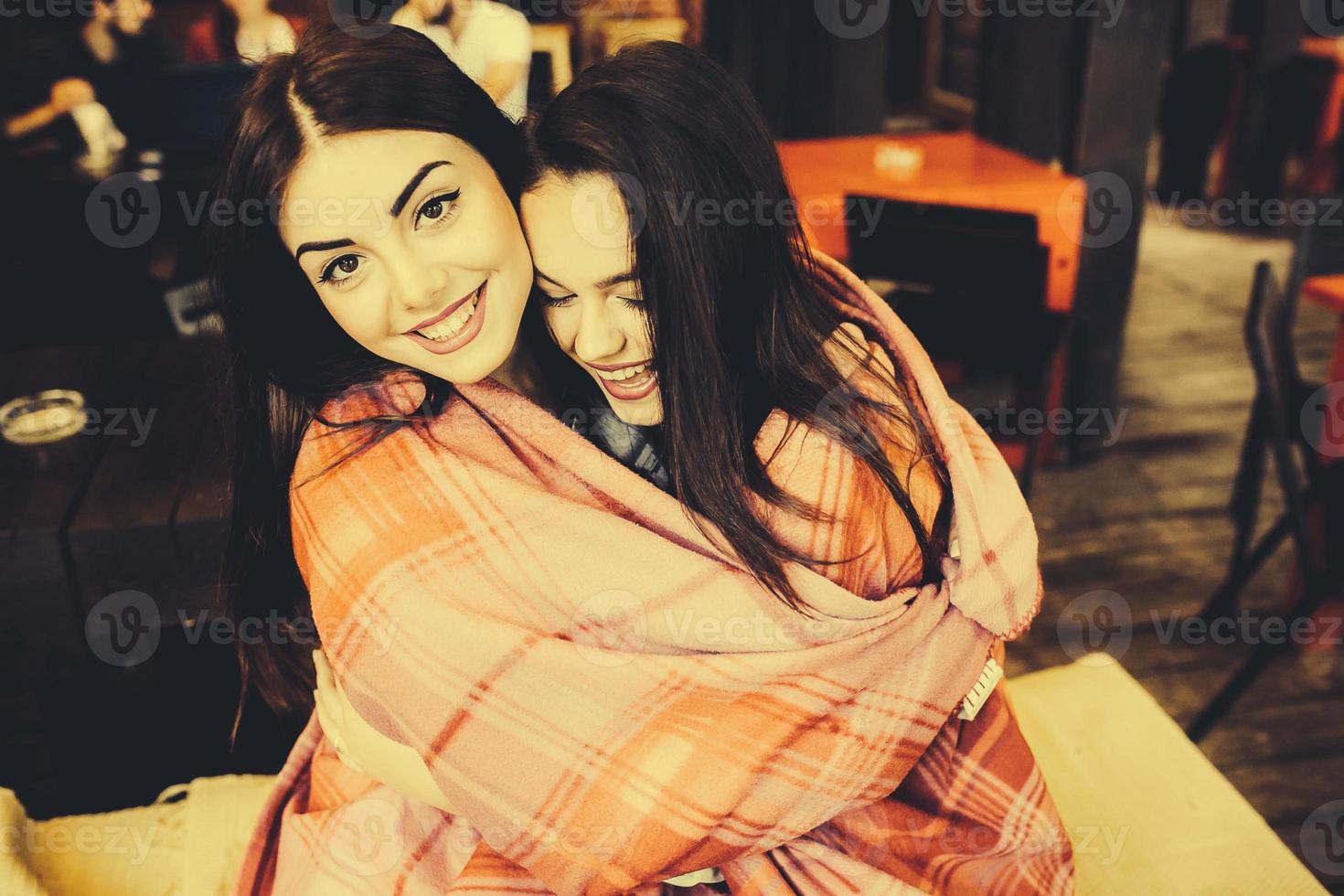 Two young and beautiful girls having fun in cafe photo