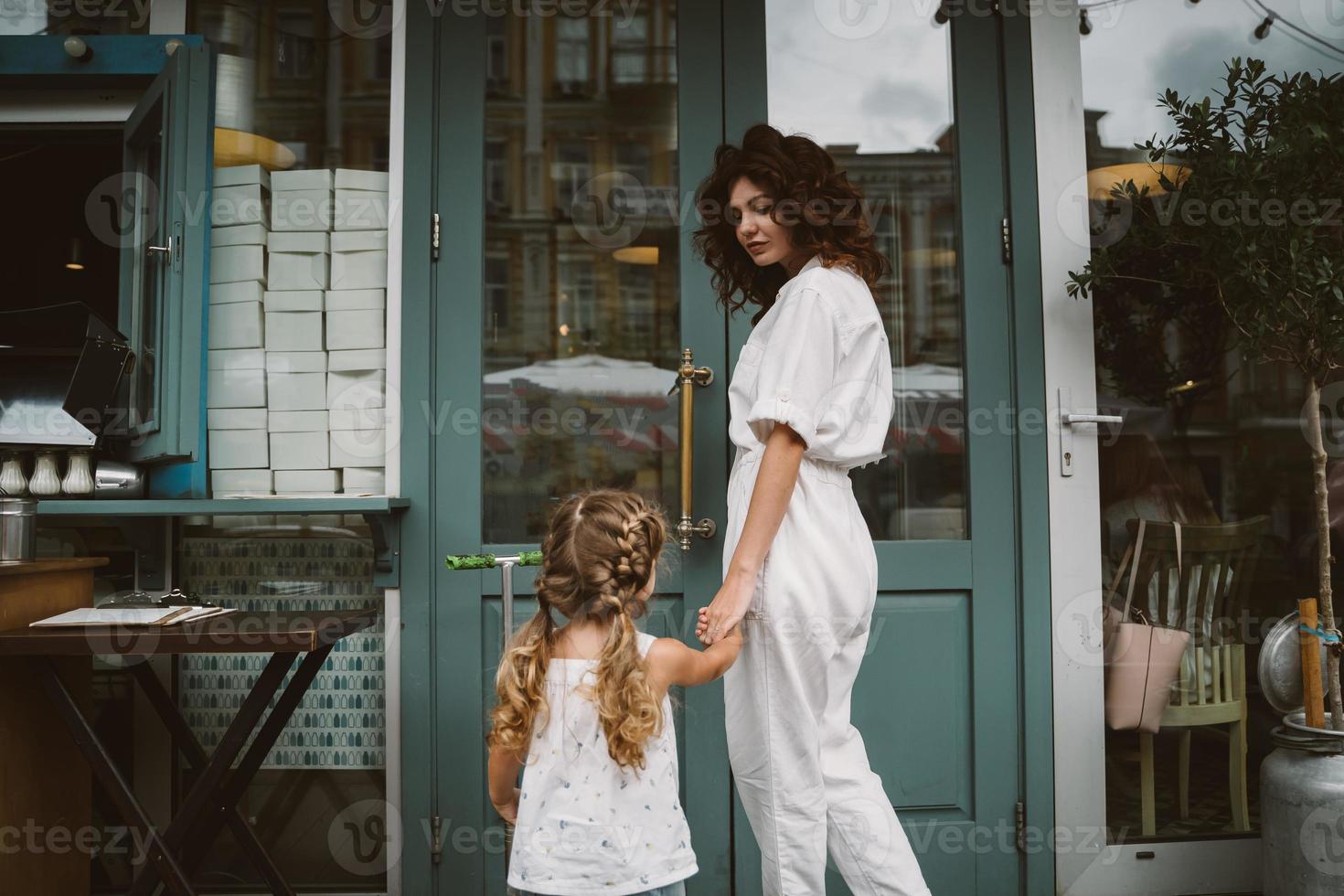 Young mother and cute little daughter walking down the street photo
