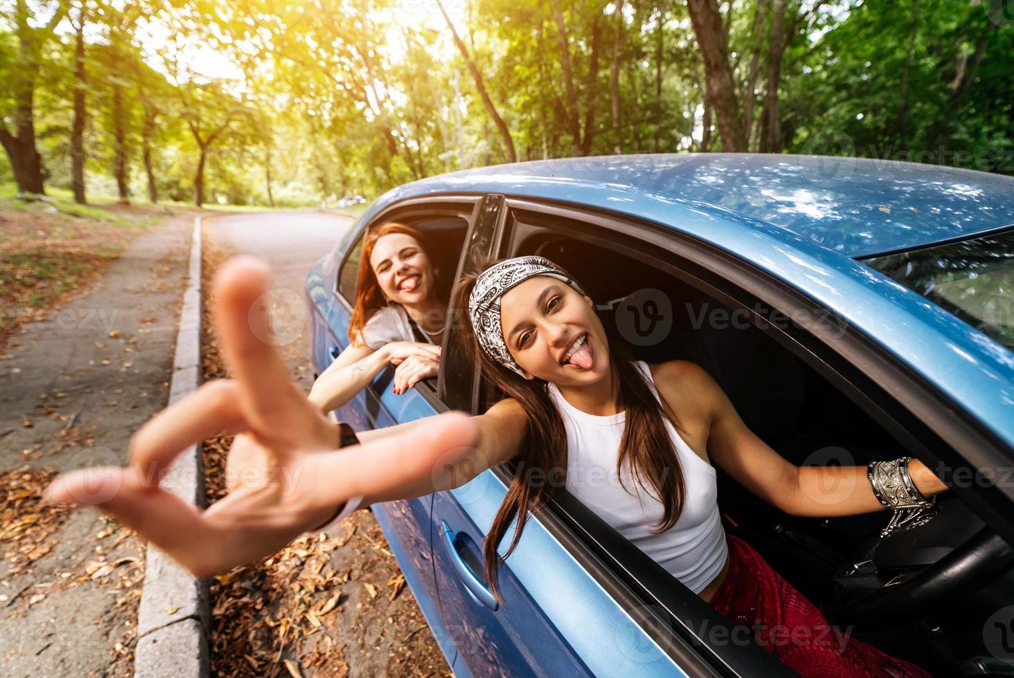 Two girlfriends fool around and laughing together in a car photo