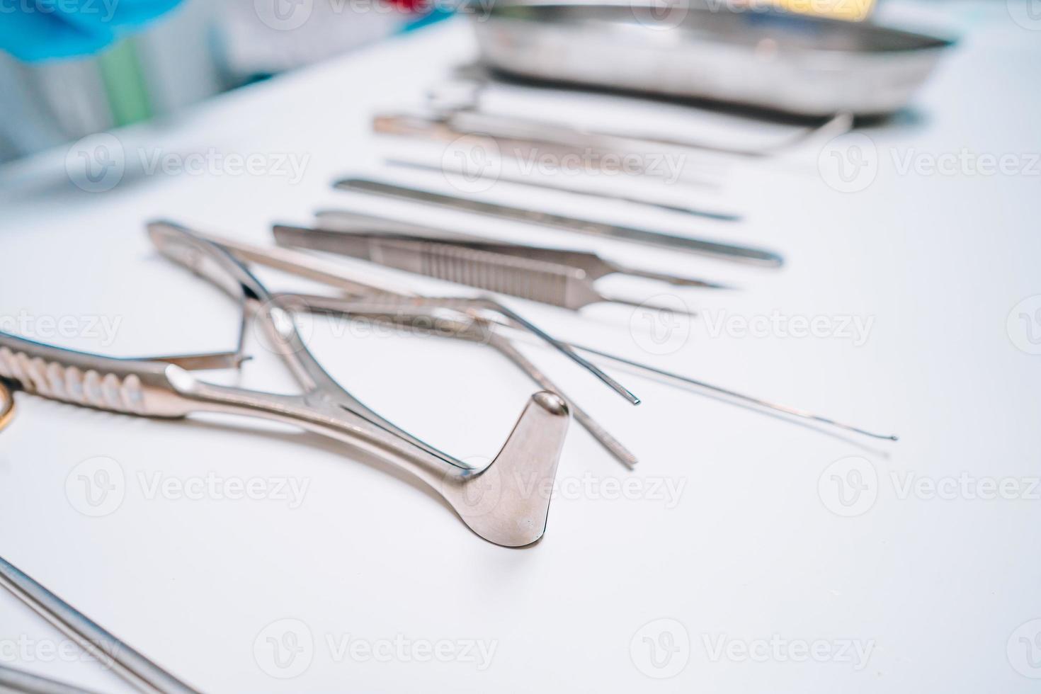 Several surgical instruments lie on a white table photo