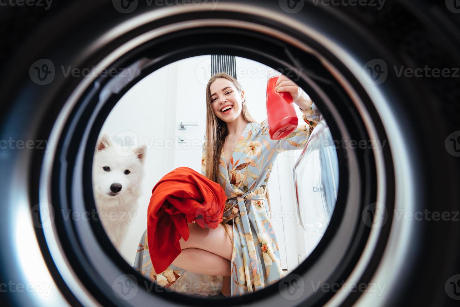 Young woman at home puts the dress in the drying machine. photo