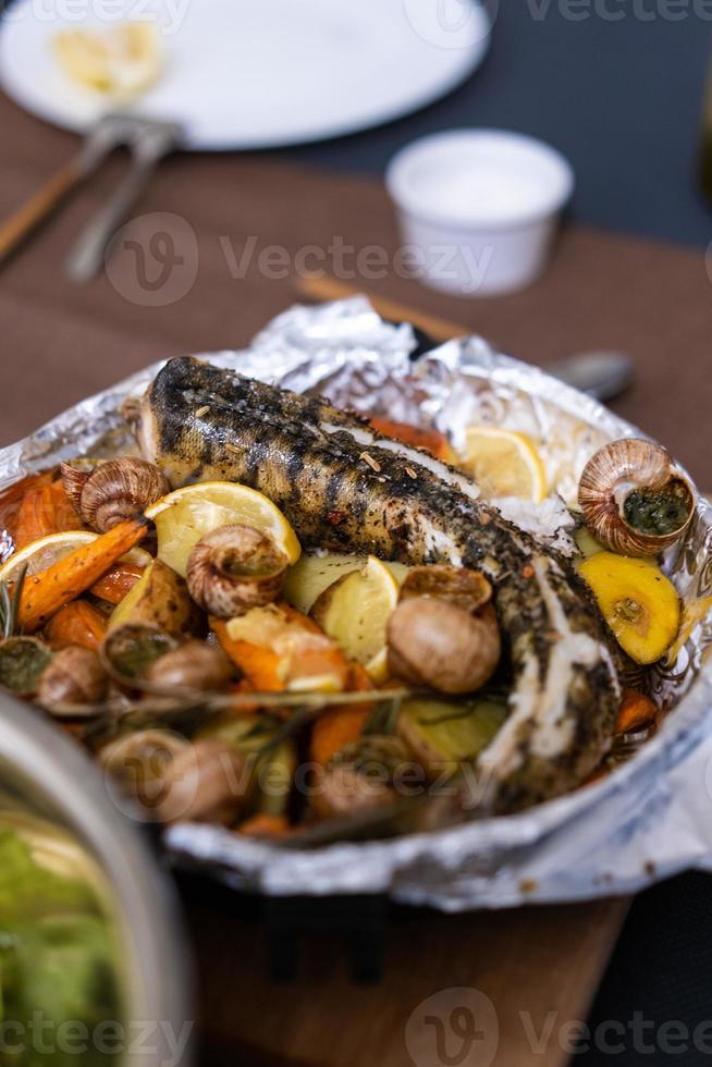 Grilled fish, sea snails with lemon and vegetables photo