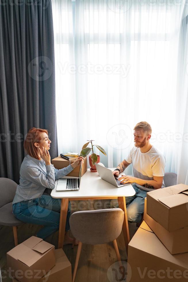 Young man and woman sitting at table, working at laptop in co-working office photo