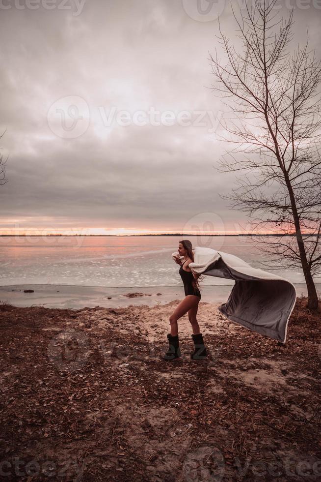 Beautiful young girl in a swimsuit on the shore of a frozen lake photo