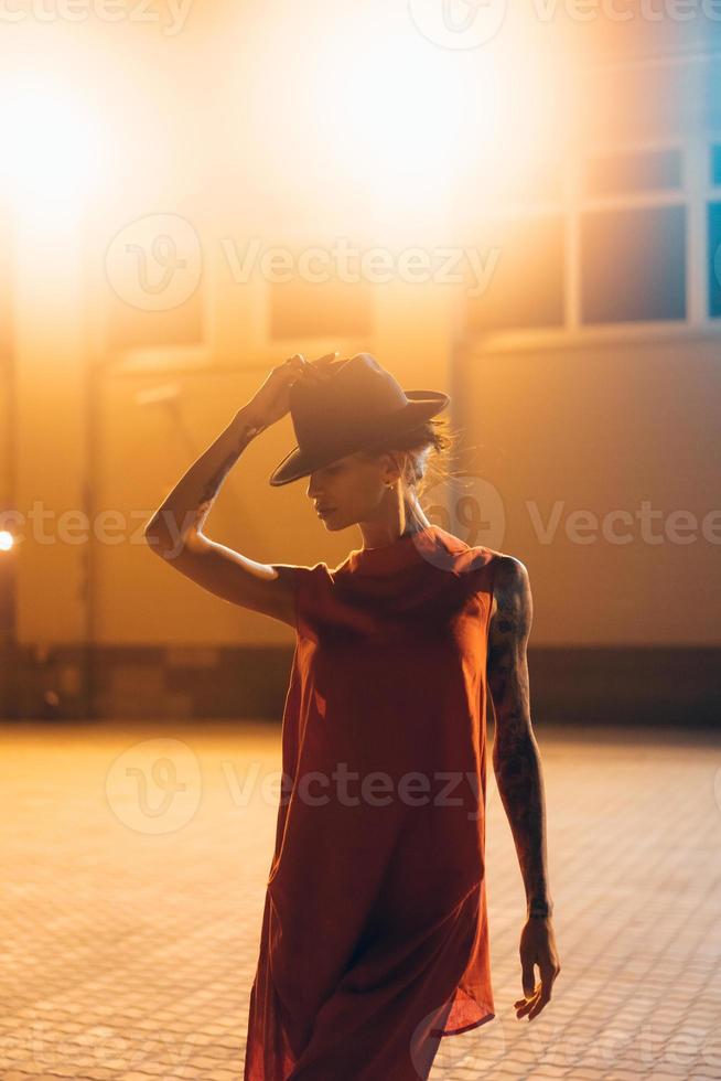 The young, attractive girl in a hat poses to the camera at night photo