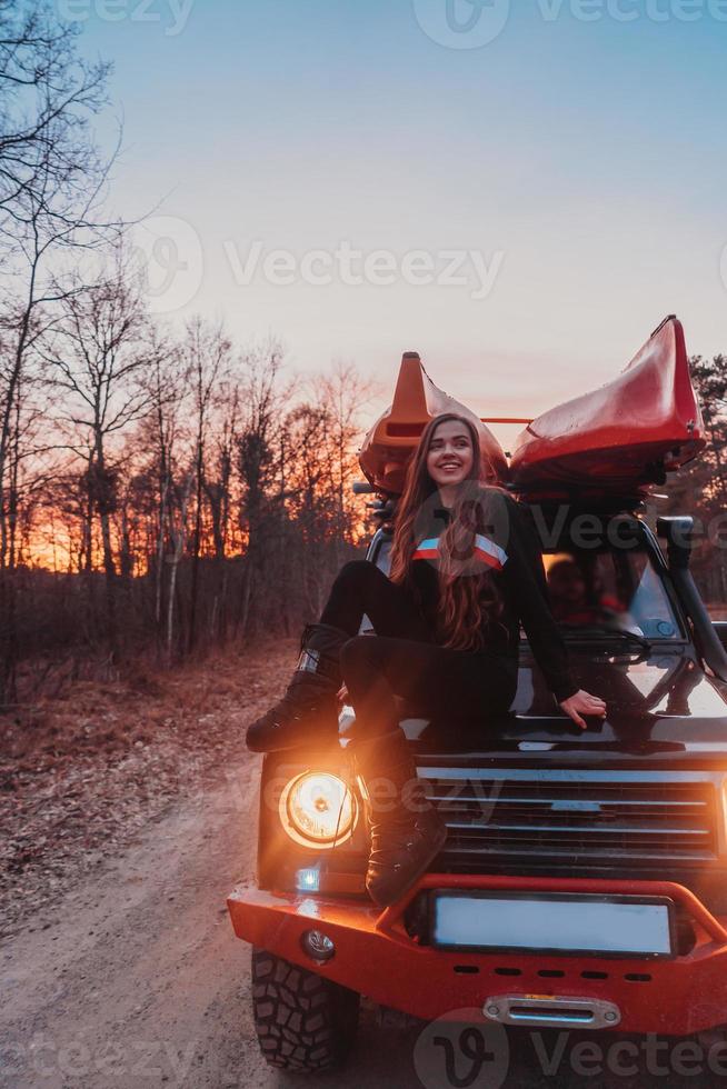 mujer sentada en la parte delantera de un vehículo todoterreno 4x4 con capó. foto