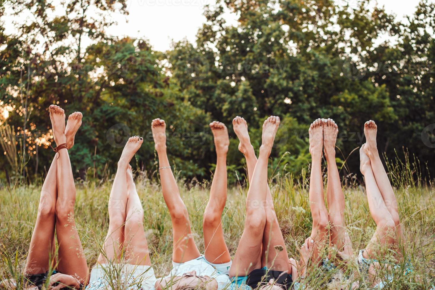 Six girls lie on the grass and raise their legs up photo