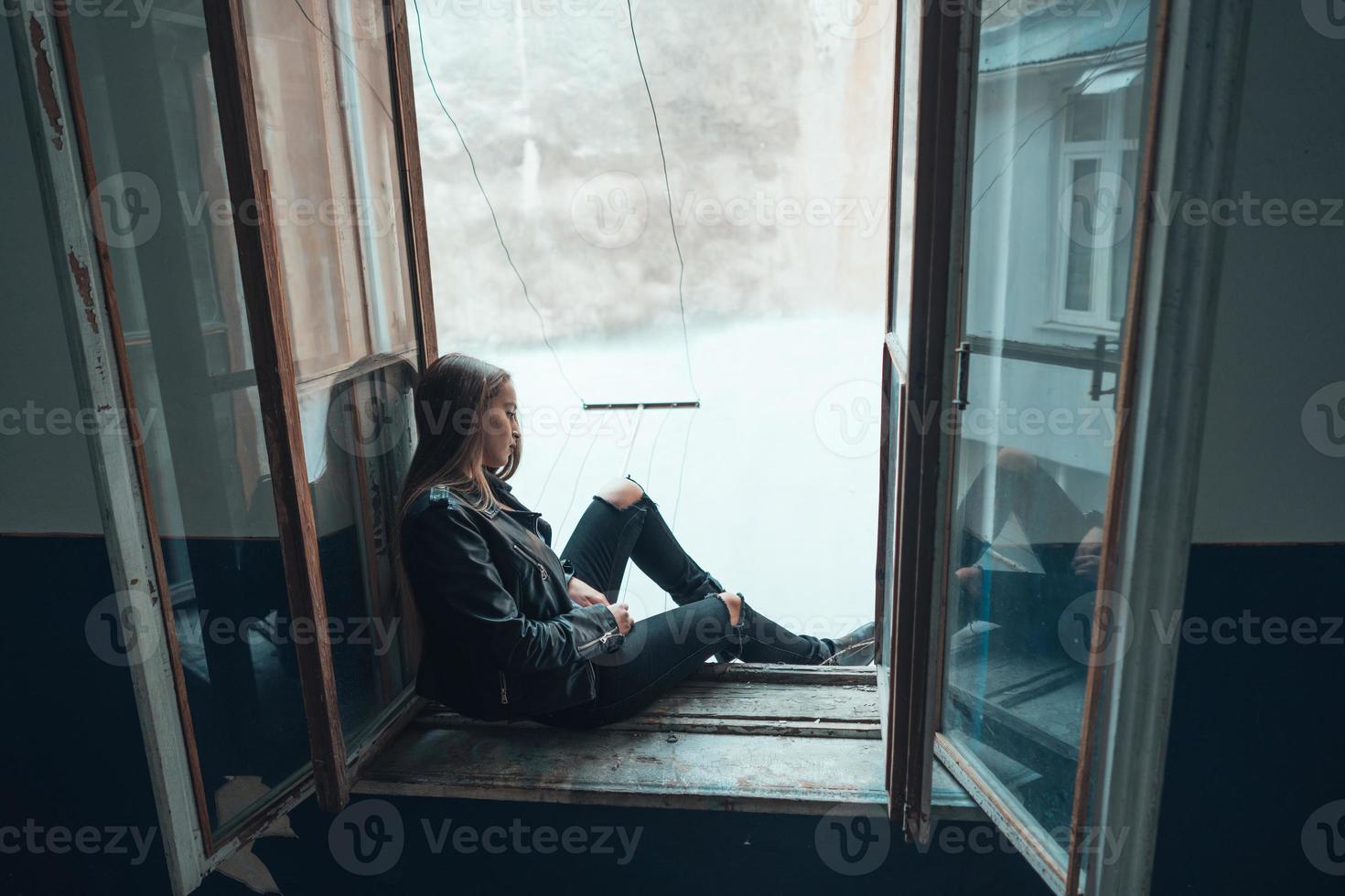 bella mujer posa en el alféizar de una ventana foto