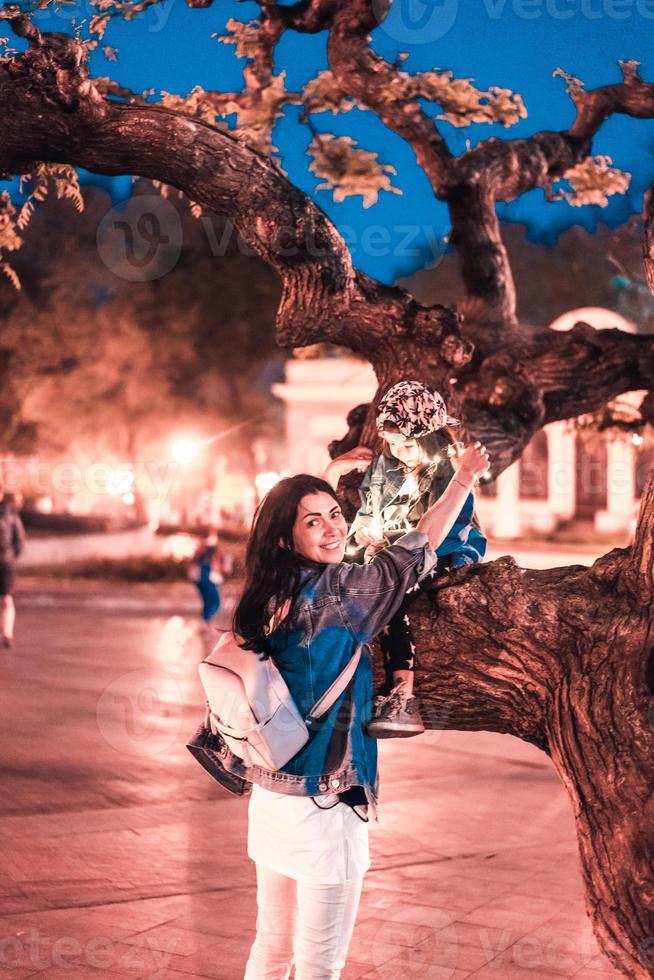 mom held up her daughter on a tree branch photo