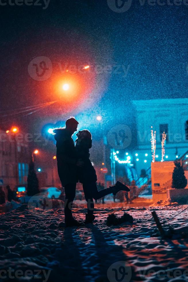 Young adult couple in each other's arms on snow covered street. photo