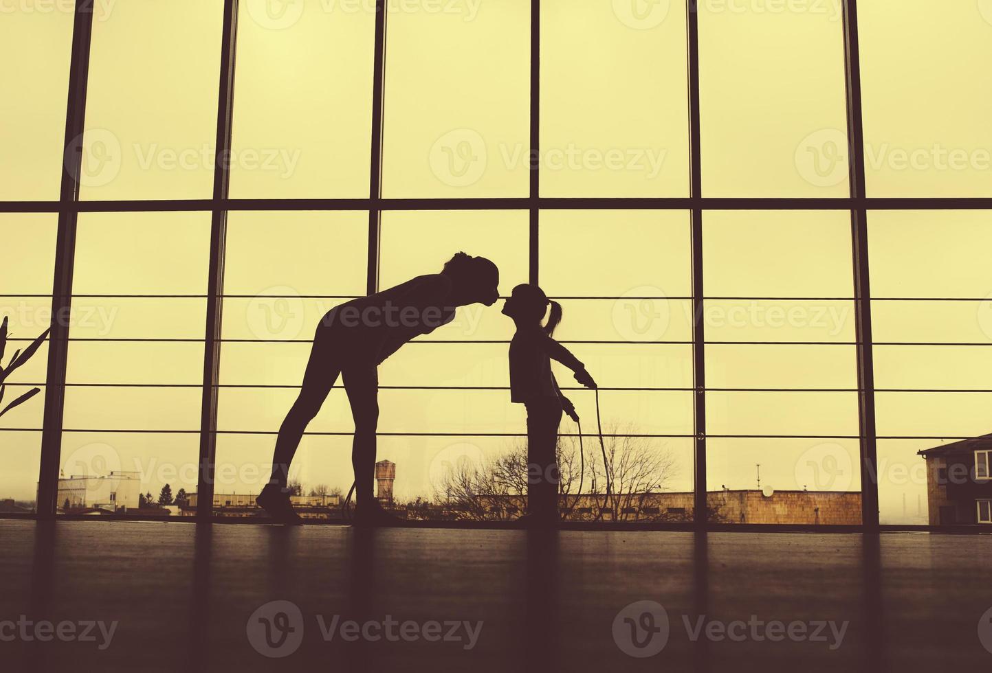 Silhouette of mother and daughter in the gym.Kiss photo