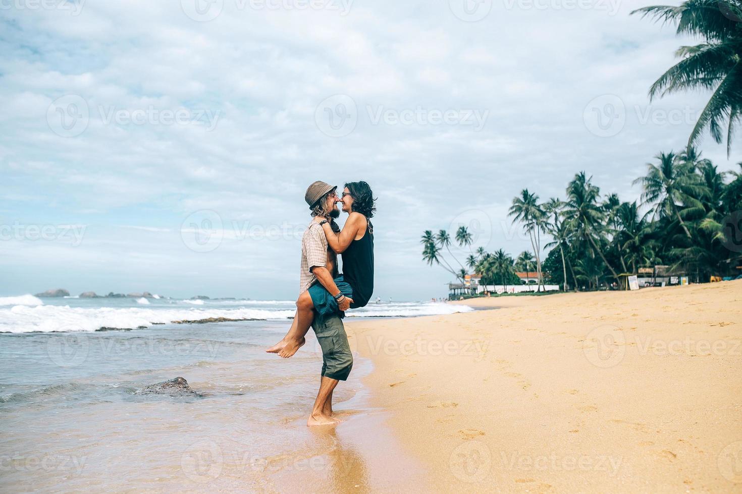 a guy and a girl are kissing on a beach photo