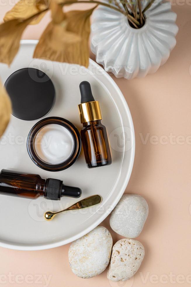 Top view of serum bottles on ceramic tray. Sustainable lifestyle concept, natural cosmetics. Unbranded Cosmetic product presentation. copy space photo