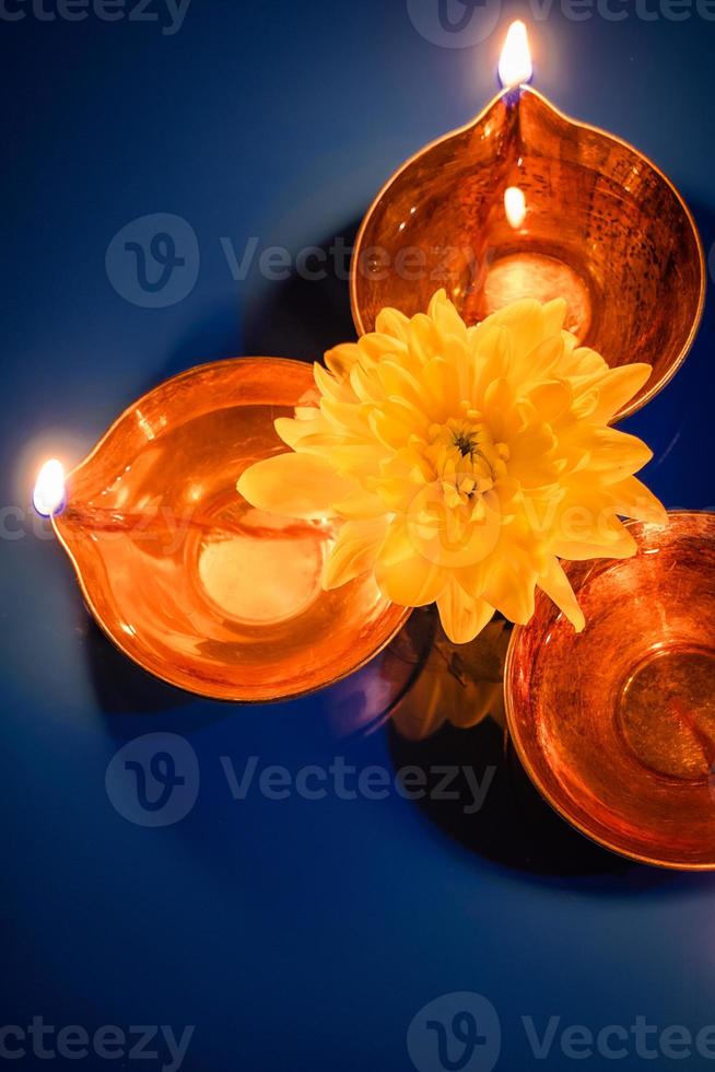 Happy Diwali. Celebrating the Hindu Light Festival. Traditional diya oil lamps and flowers on blue background. photo