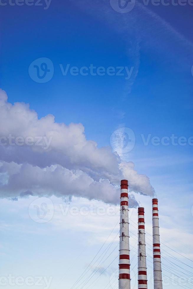 Air pollution. Smoking chimneys against blue sky. photo