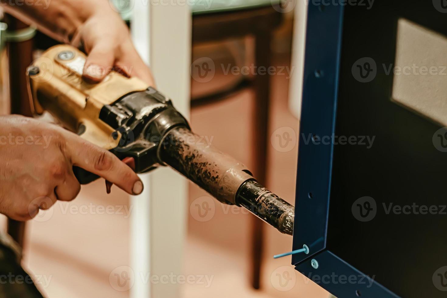 Male worker uses electric riveting gun. Hand holding riveting m photo