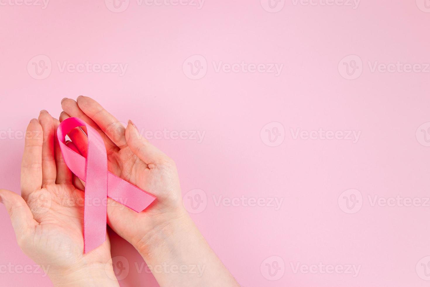 Breast Cancer Awareness Month. Woman's hand holds pink ribbon. Health care concept, cancer control symbol. photo