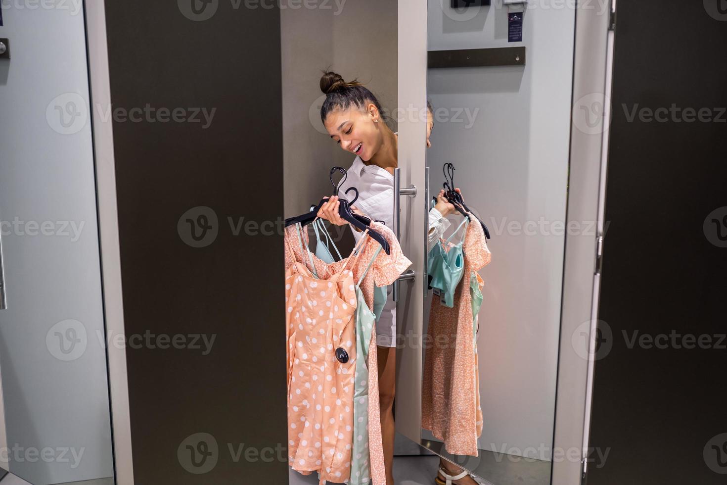 Beautiful girl with lots clothes in room background in a boutique photo