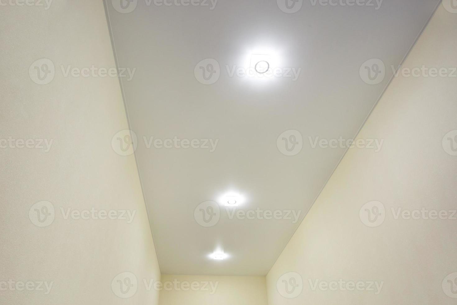 suspended ceiling with halogen spots lamps and drywall construction in empty room in apartment or house. Stretch ceiling white and complex shape. photo