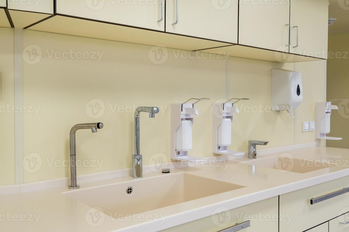elbow soap and antiseptic dispenser or sanitizer wall mounted for hand disinfection and water tap sink with faucet bathroom or clinic photo