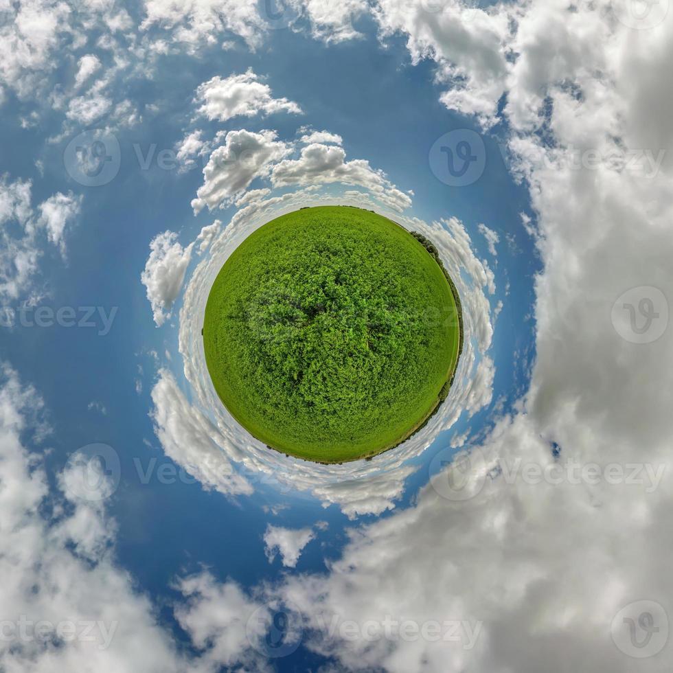 green tiny planet in blue sky with beautiful clouds. Transformation of spherical panorama 360 degrees. Spherical abstract aerial view. Curvature of space. photo