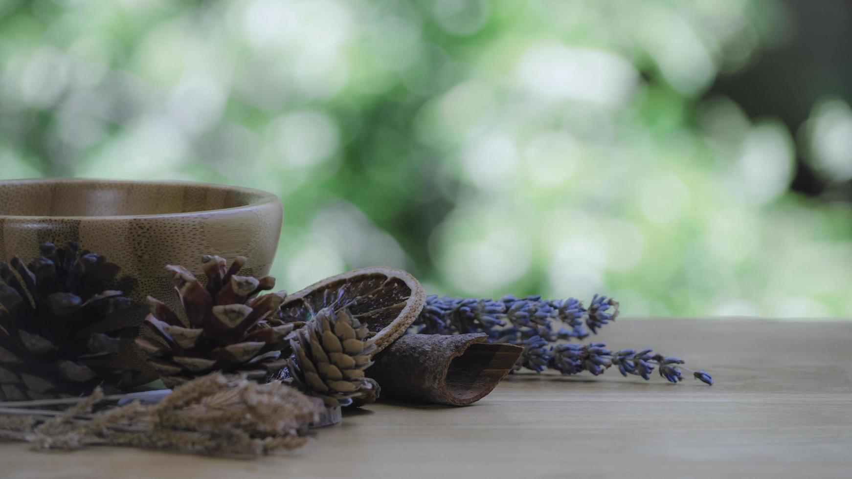 Dark glass bottle with essential oil blend with cinnamon, dried citrus slice, pine twigs, cones and wooden background. Nature home deodorants and warm toned. photo