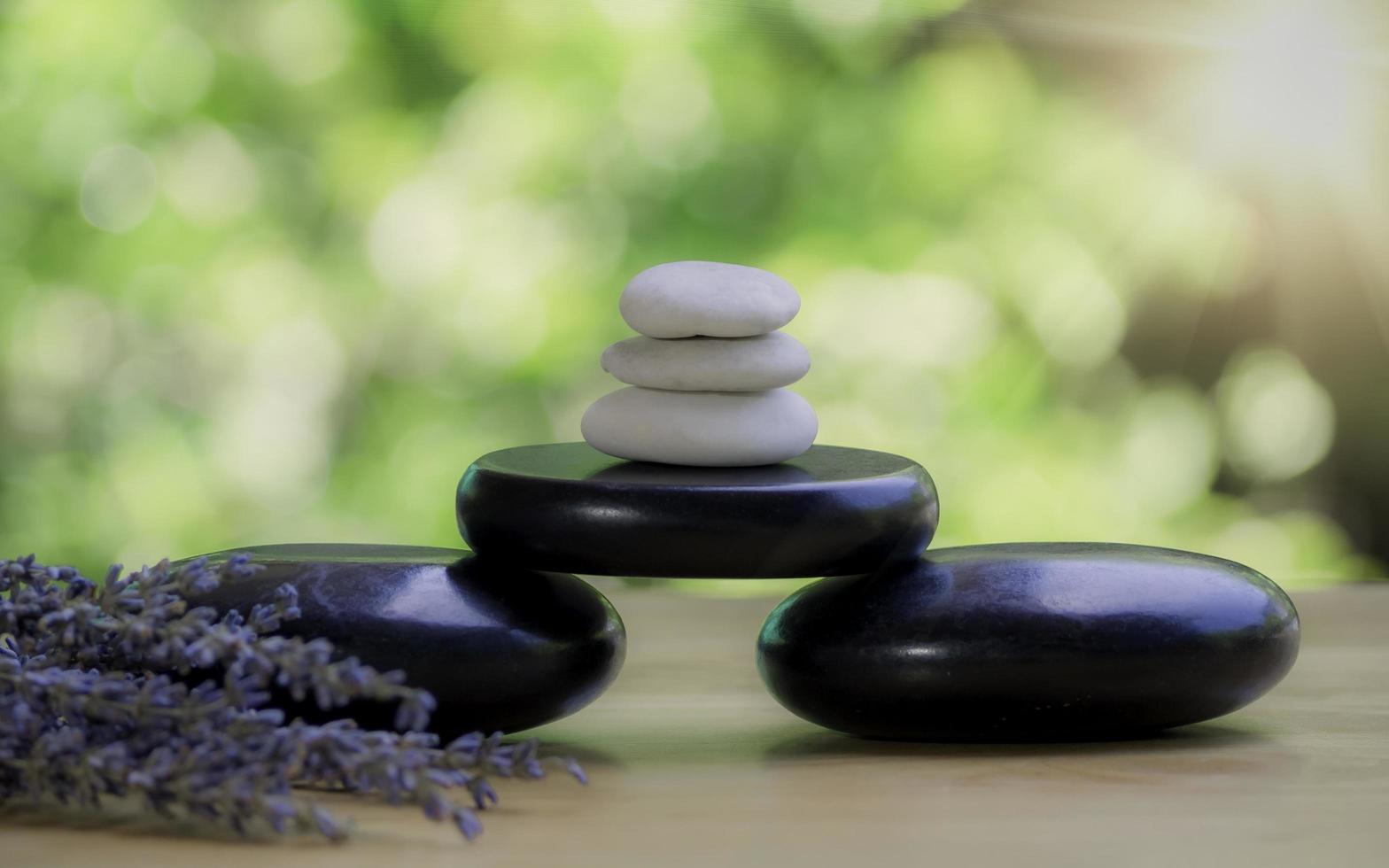 Balance and wellness or health concept with pile of black spa stones on wood and spikes of flowering lavender with aromatherapy. Side view and landscape composition feel relaxed. photo