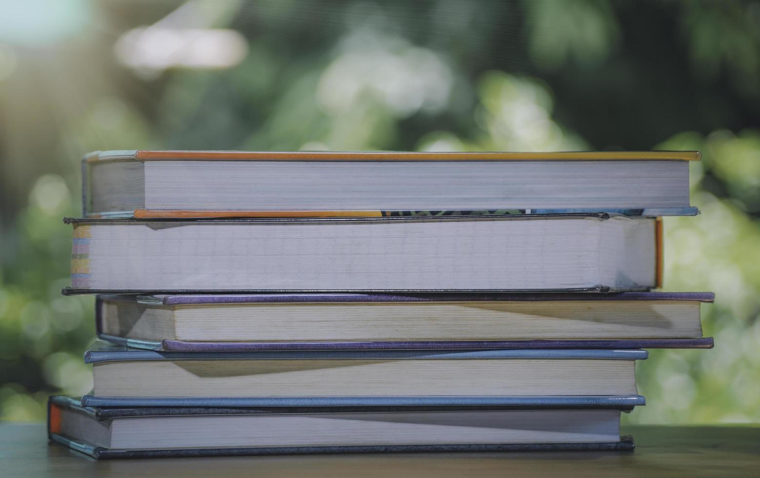 una composición simple de muchos libros, pila o pila de libros sobre una mesa de madera, uno de ellos abierto con espacio para copiar. foto