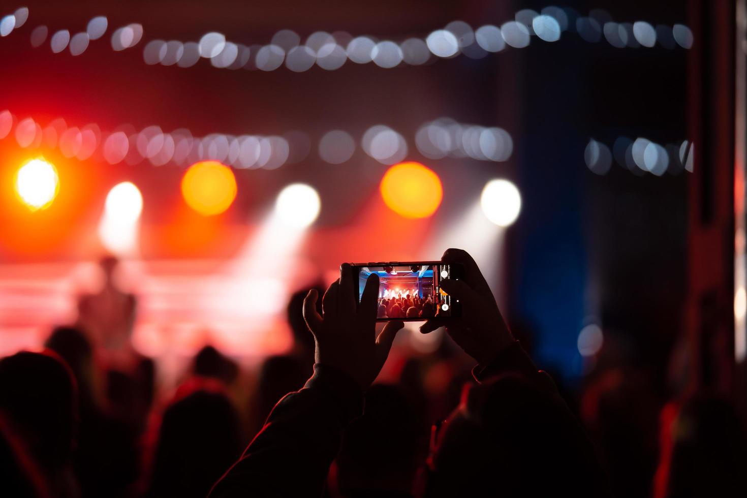 Person close up of recording video with smartphone during a concert. photo