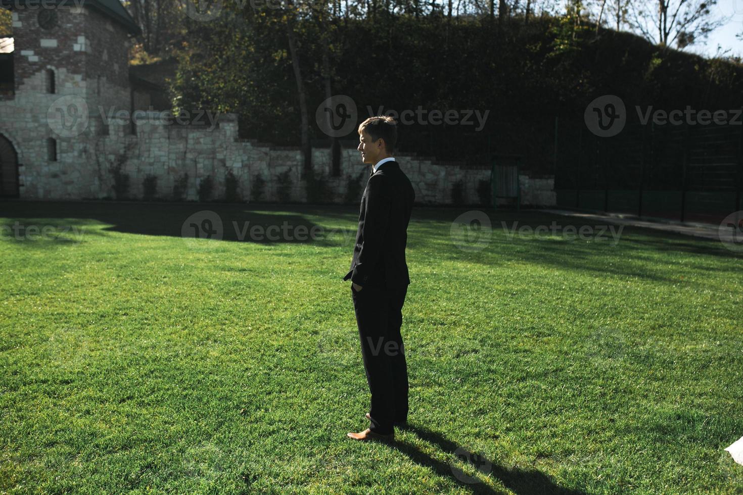 groom standing on the grass photo