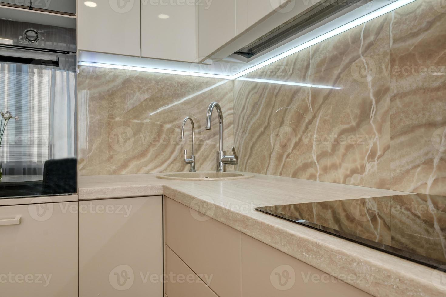 Interior of the small living equipped kitchen in studio apartments in minimalistic style with light color photo