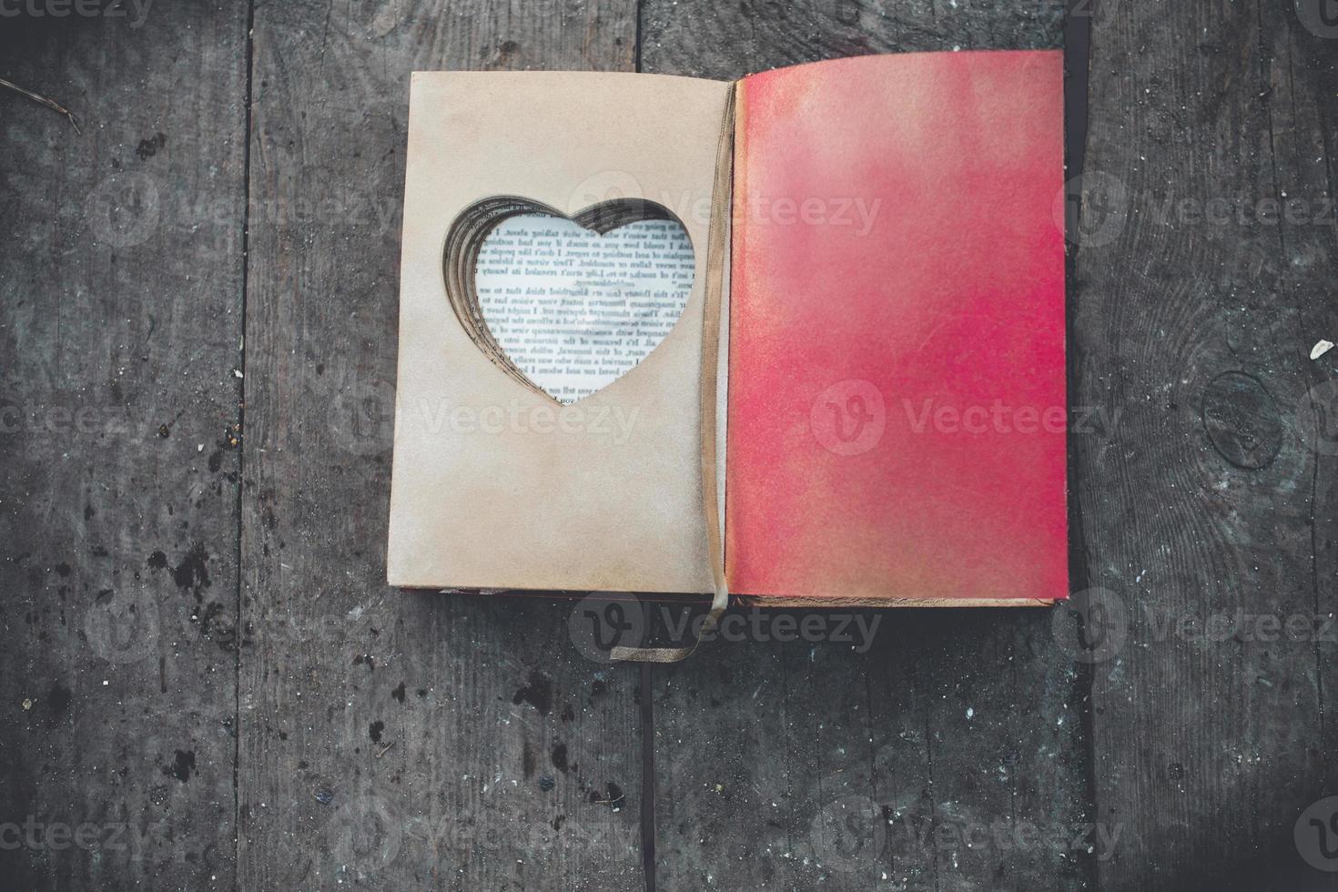 encantador libro vintage con corazón hecho a mano en el que descansa el anillo. foto
