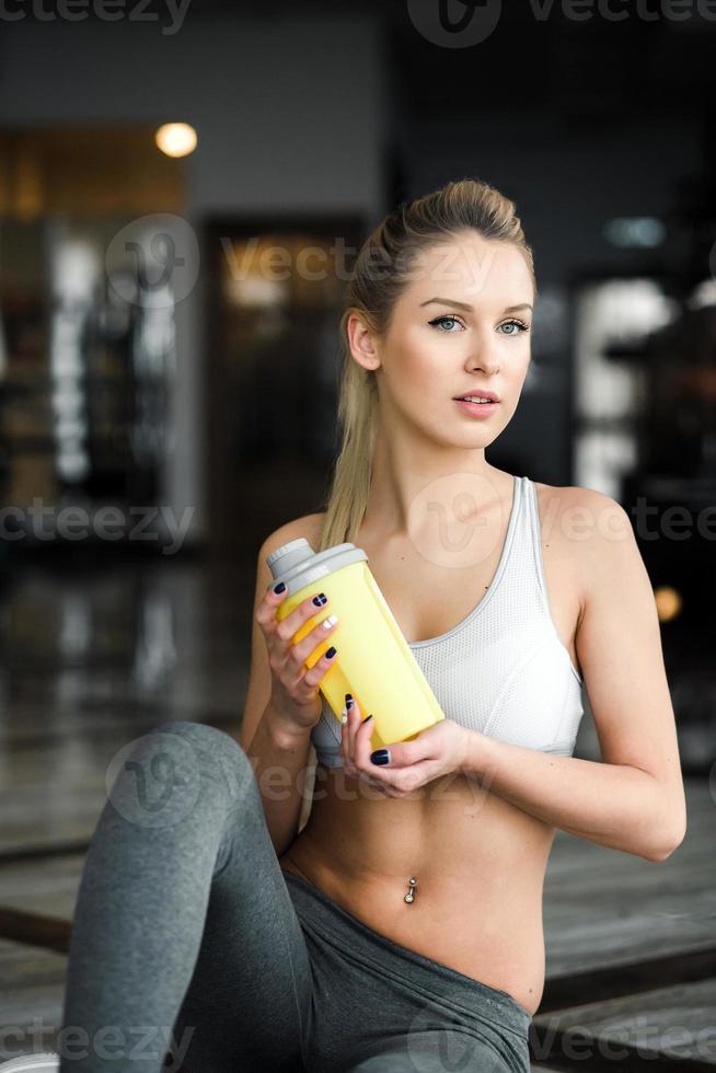 Beautiful athletic girl poses in the gym with a yellow shaker. 11485570